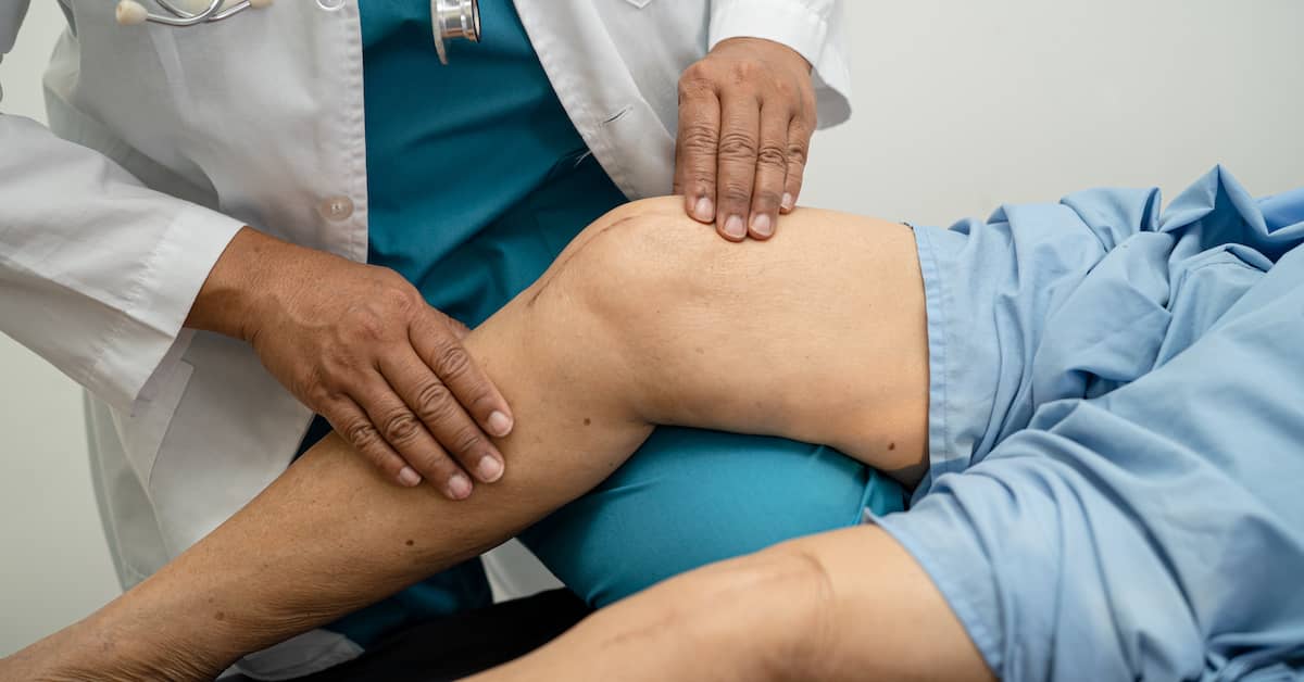 doctor examining patient's knee after knee replacement surgery