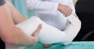 doctor applying bandages to a worker's injured leg