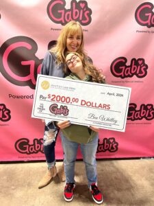Two members of Gabi's Powered by Special Abilities pose with a $2,000 check from Whitley Law Firm