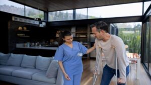 Injured Man Walking on Crutches with the Help of His Nurse