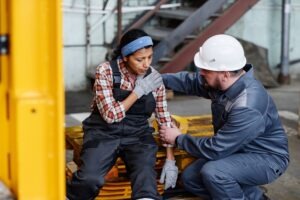 A worker helping another employee. Discuss compensation with a Raleigh workplace injury lawyer.