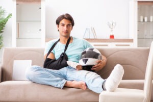 Injured man sits on couch and holds helmet after motorcycle accident in North Carolina.