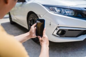 A man takes a photo of his damaged car and wonders what to do after a minor car accident.