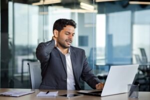 A man working on a computer rubs his neck and wonders how long after a car accident injuries can appear.