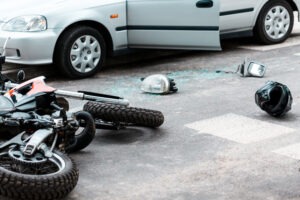 An overturned motorcycle and helmet lay on the road after a collision with a car. What damages can I collect for a motorcycle accident?